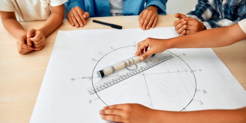 Schoolchildren, together with the teacher, are sitting at a desk in the lesson and studying the trigonometric circle. Back to school. The concept of science and education.