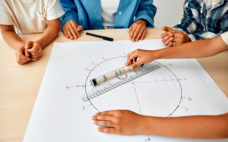 Schoolchildren, together with the teacher, are sitting at a desk in the lesson and studying the trigonometric circle. Back to school. The concept of science and education.