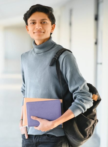 Portrait of indian college boy holding books.
