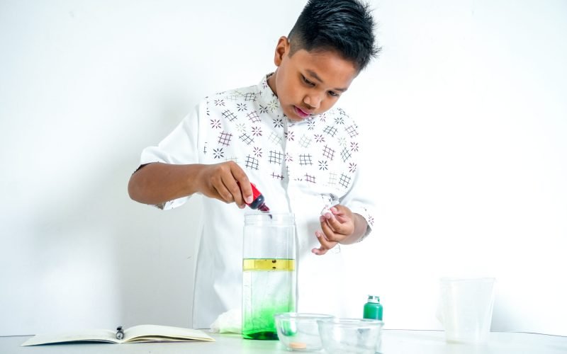 Young Asian Student Adding Red Food Coloring To Density Tower Experiment At Home